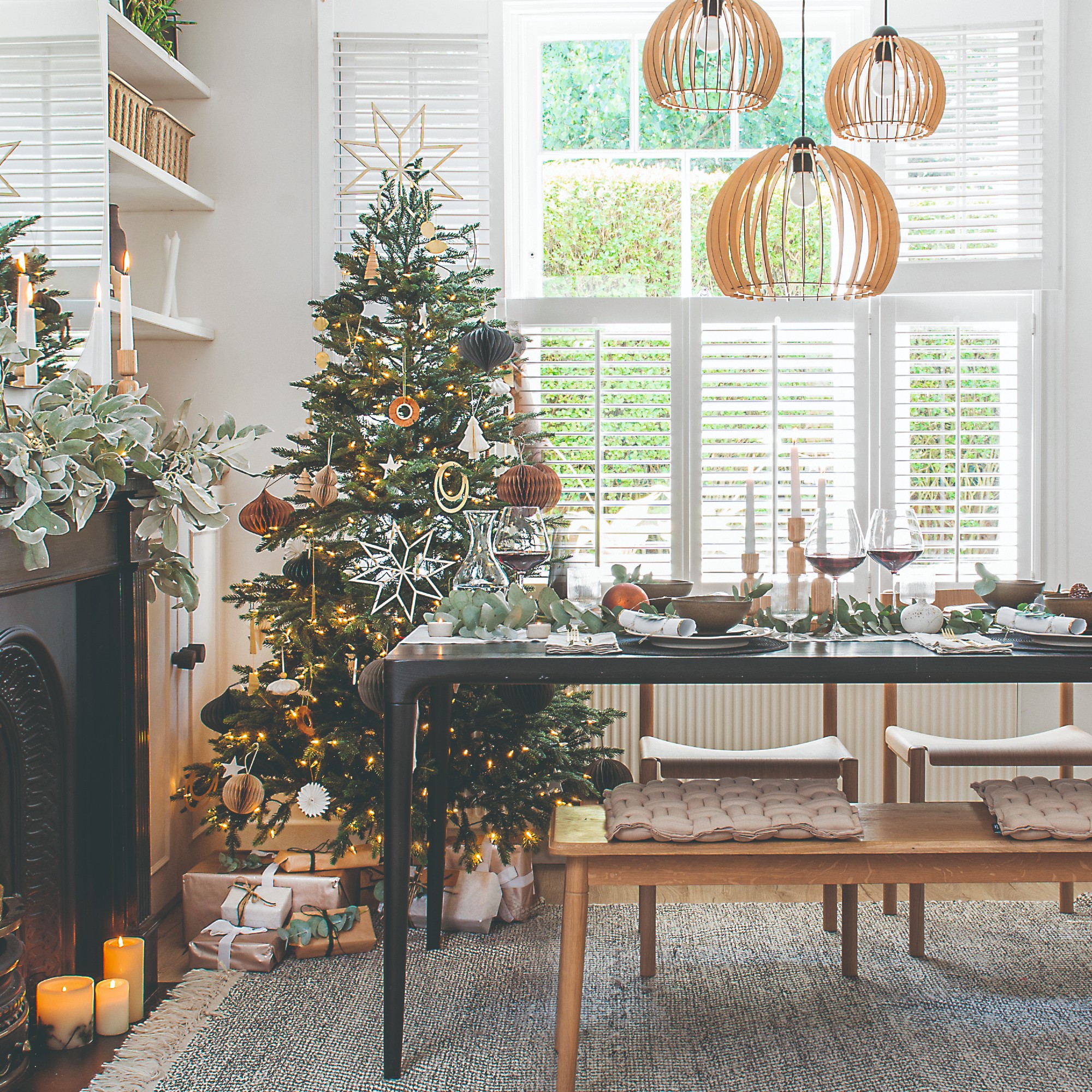 A dining area decorated for Christmas with a Christmas tree with presents in the corner