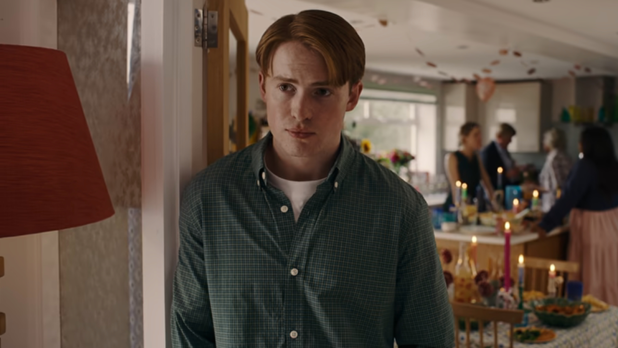 Kit Connor as Nick Nelson, leaning against a door frame at a party in Heartstopper Forever.