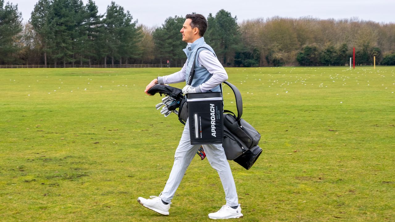 Golfer carrying Garmin R50 in case on driving range