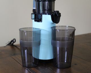 Dash Compact Juicer with two plastic cups on wooden table