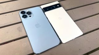 pixel 6 pro vs iphone 13 pro max: both phones laying face down on a table