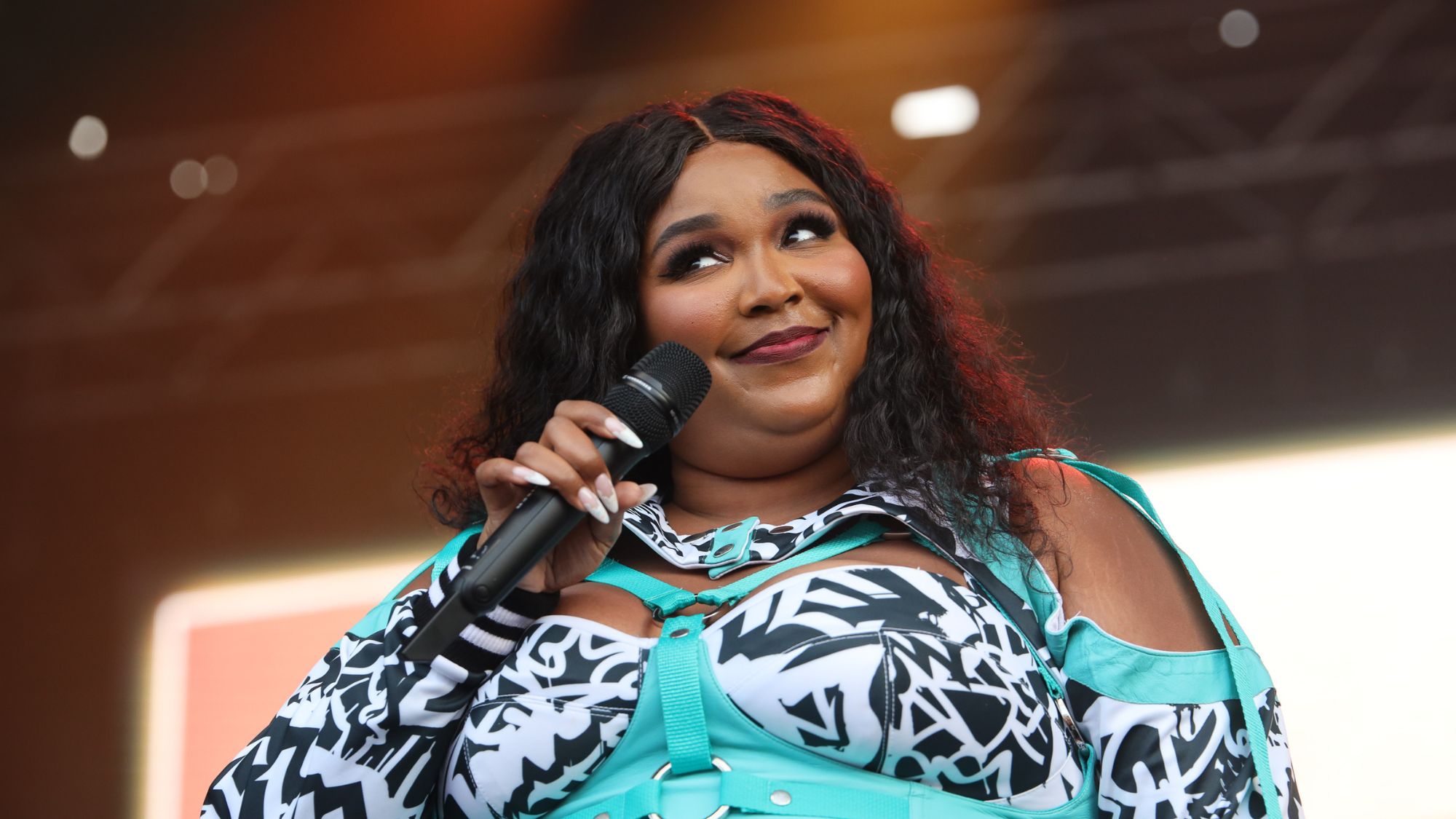 Lizzo performs on stage in a green, black and white top