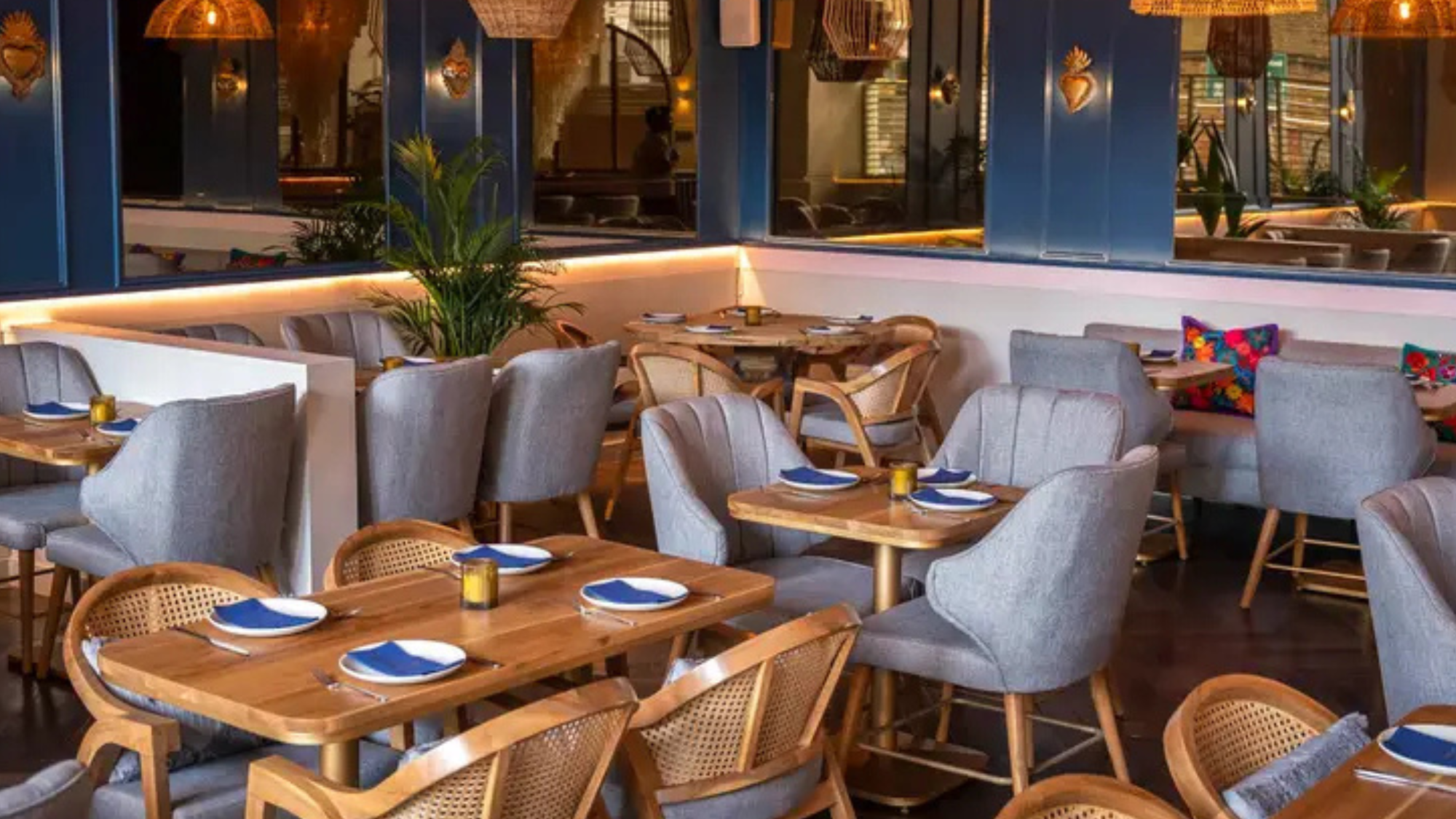 Wide shot of the dining area in Mestizo with wooden tables, grey chairs and blue walls