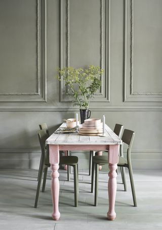 pink and off white painted wooden table with olive green painted chairs and walls