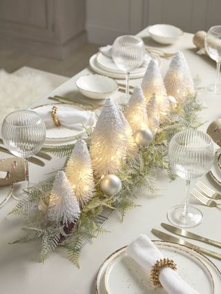 tow of white faux Christmas trees in the middle of a festive table