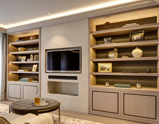 beige living room with tv on the wall and recessed led lighting in the shelves