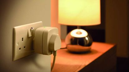 Smart plug in use to control a lamp, which is positioned on a side table in a corridor