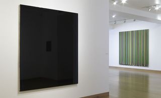 A gallery with a square screen and a painting made of many colourful vertical lines on the wall.