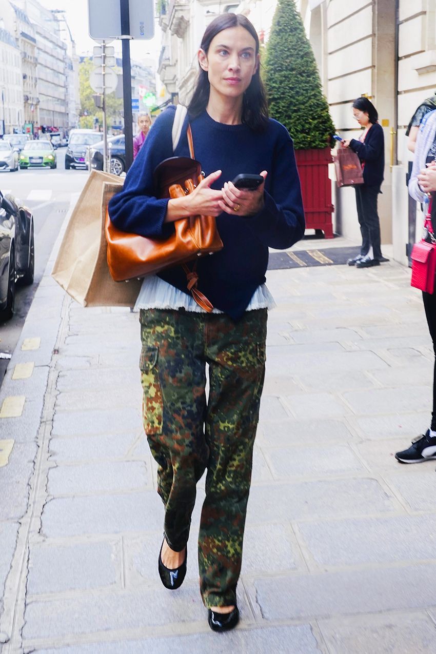 Alexa Chung wearing a navy sweater over a camisole with camo pants and black ballet flats.