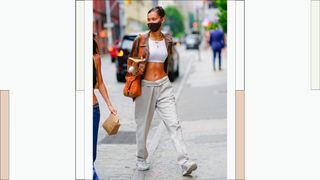 Bella Hadid wears the waistband of her cream-colored trousers folded over as she's seen with a friend in Soho on August 12, 2020 in New York City