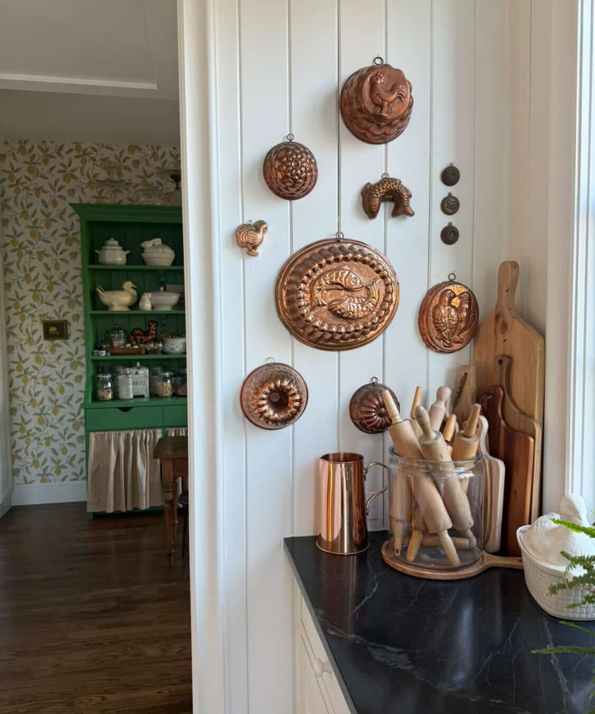 A new build kitchen with white paneled walls decorated with a range of copper molds