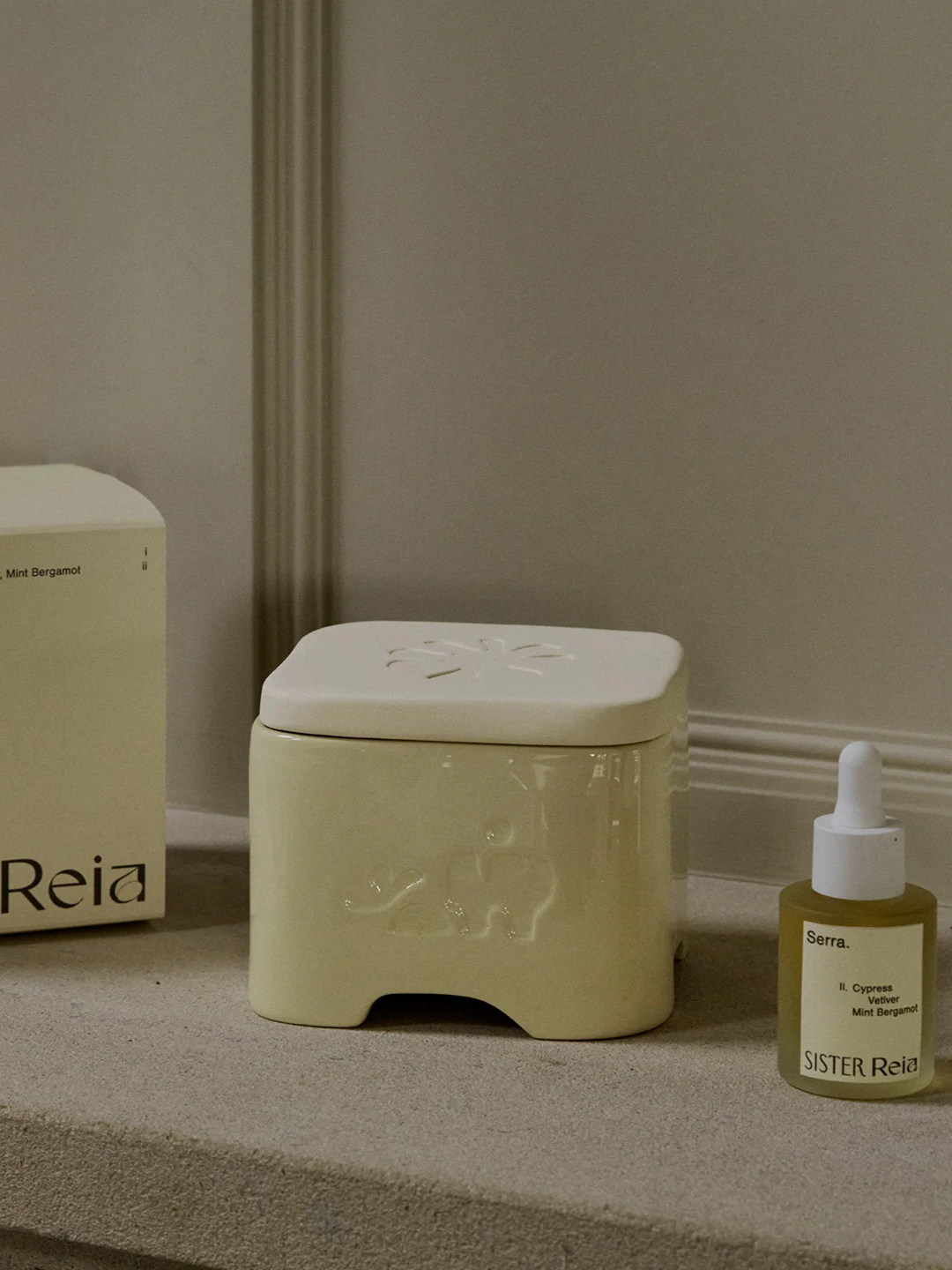 A yellow ceramic-metal diffuser beside a bottle of scented oils from Reia x Sister by Studio Ashby