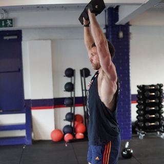 Man demonstrates midway position of the dumbbell overhead press