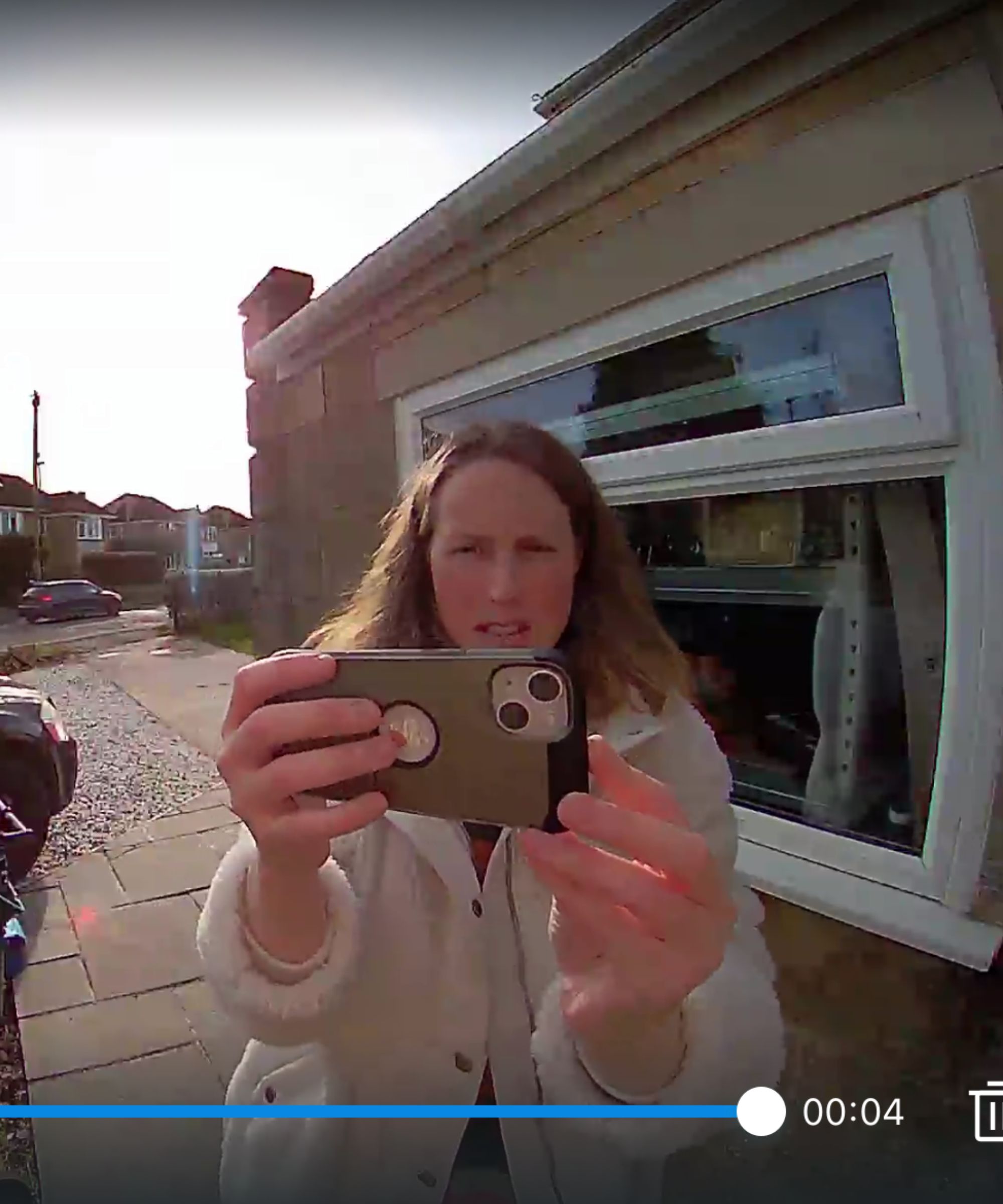 Screenshot of the Tapo app showing screen of Jennifer Oksien pointing phone camera at the Tapo D210 Video Doorbell, with window and house in background.