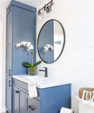 Coastal bathroom with white wood walls and blue cabinets