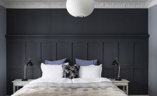 Hotel guest bedroom with dark grey wall to ceiling headboard and grey interior