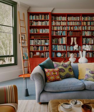 Living room with floor to ceiling red bookcase and grey couch