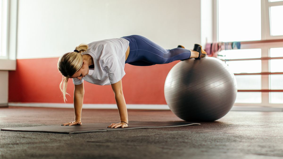 Woman holds plank with feet resting on a Swiss ball