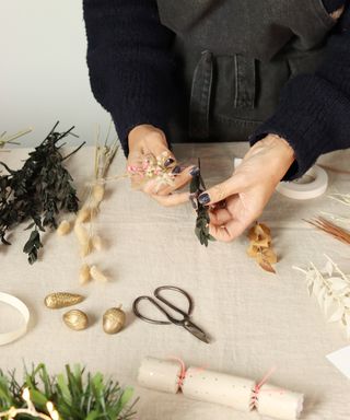 Hands making small bunches of dried flowers to attach to a wreath