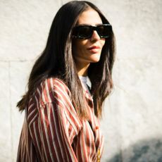 A woman with chocolate hair wearing sunglasses and a striped shirt