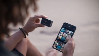 DJI Osmo Action review: a person sits on a beach using the DJI Osmo Action with the Mimo app