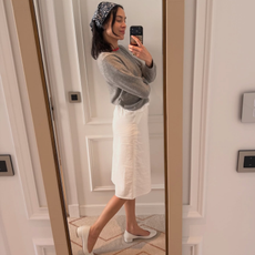 Alexa Chung wears a heeled ballet flat and midi skirt. She finishes with a paisley print headscarf and grey jumper. 