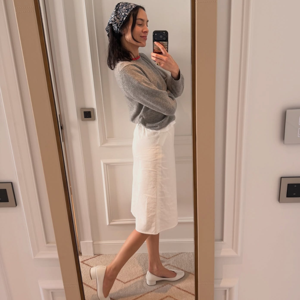 Alexa Chung wears a heeled ballet flat and midi skirt. She finishes with a paisley print headscarf and grey jumper. 