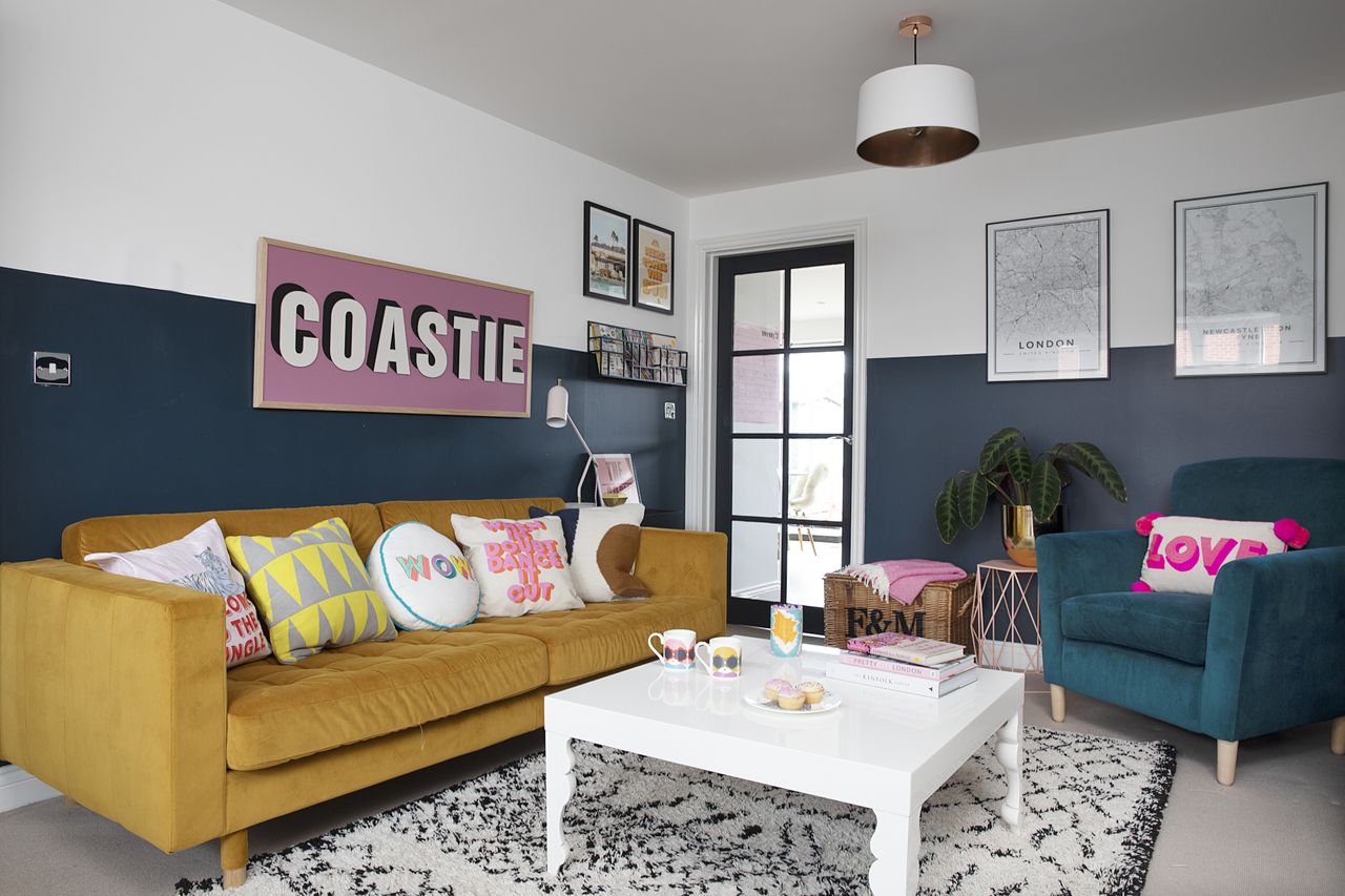 Blue living room with monochrome Scandi rug, white coffee table, yellow sofa, teal armchair and large &#039;Coastie&#039; pink print