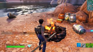 Fortnite - a player stands in front of a lit campfire