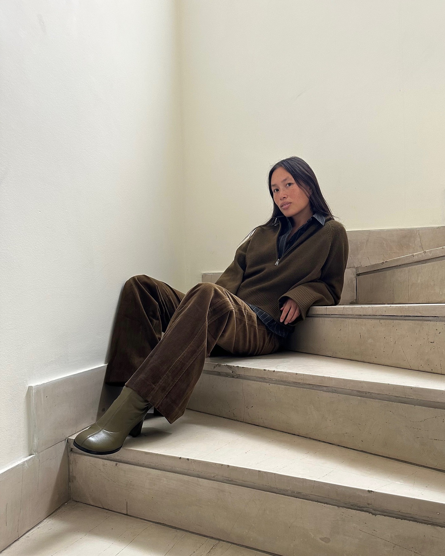 Influencer @vikilefevre wears brown corduroy trousers with olive sock boots and a khaki knit.