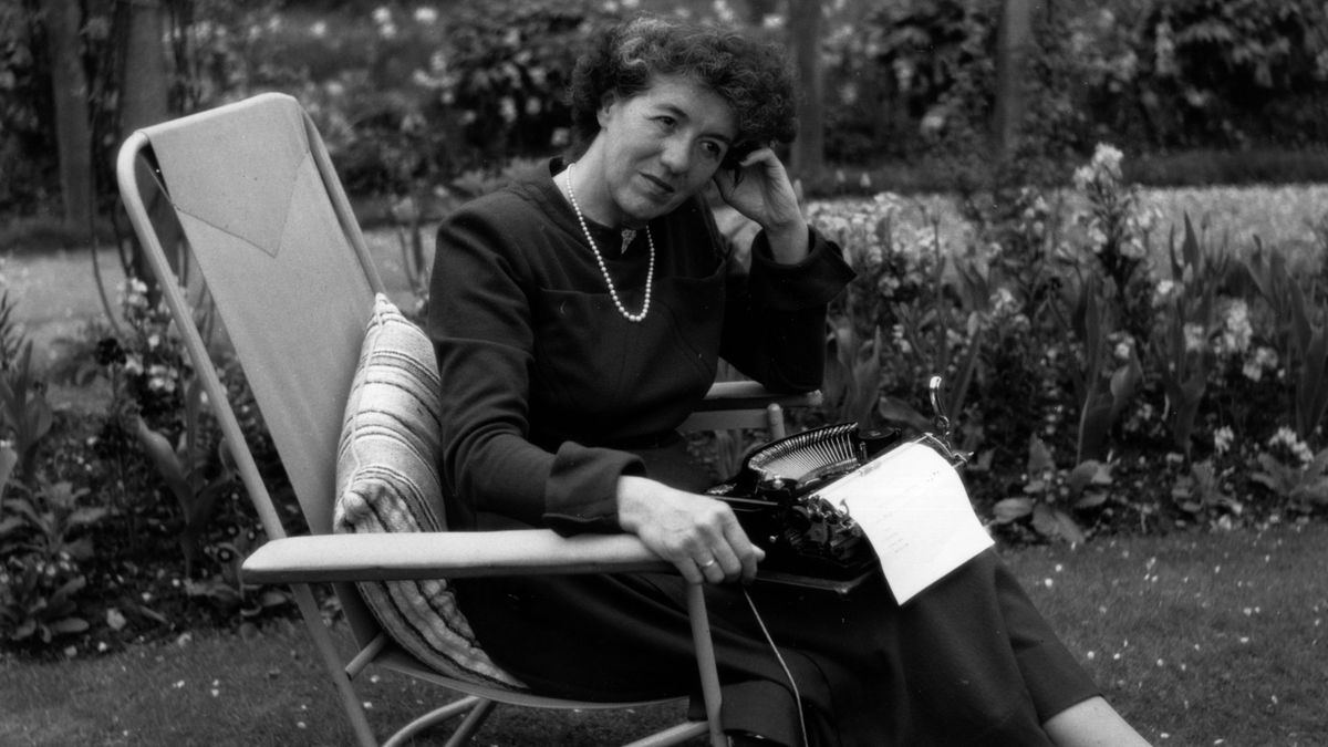 Black and white image of Enid Blyton (1897-1968) sitting in her garden in Buckinghamshire. 