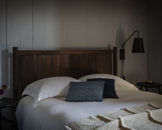 A bedroom with dark wooden bed and blue throw pillows