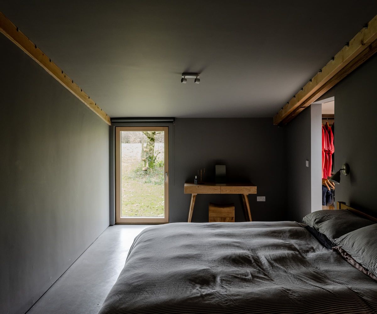 A completely black bedroom with a windowed door and walk in wardrobe