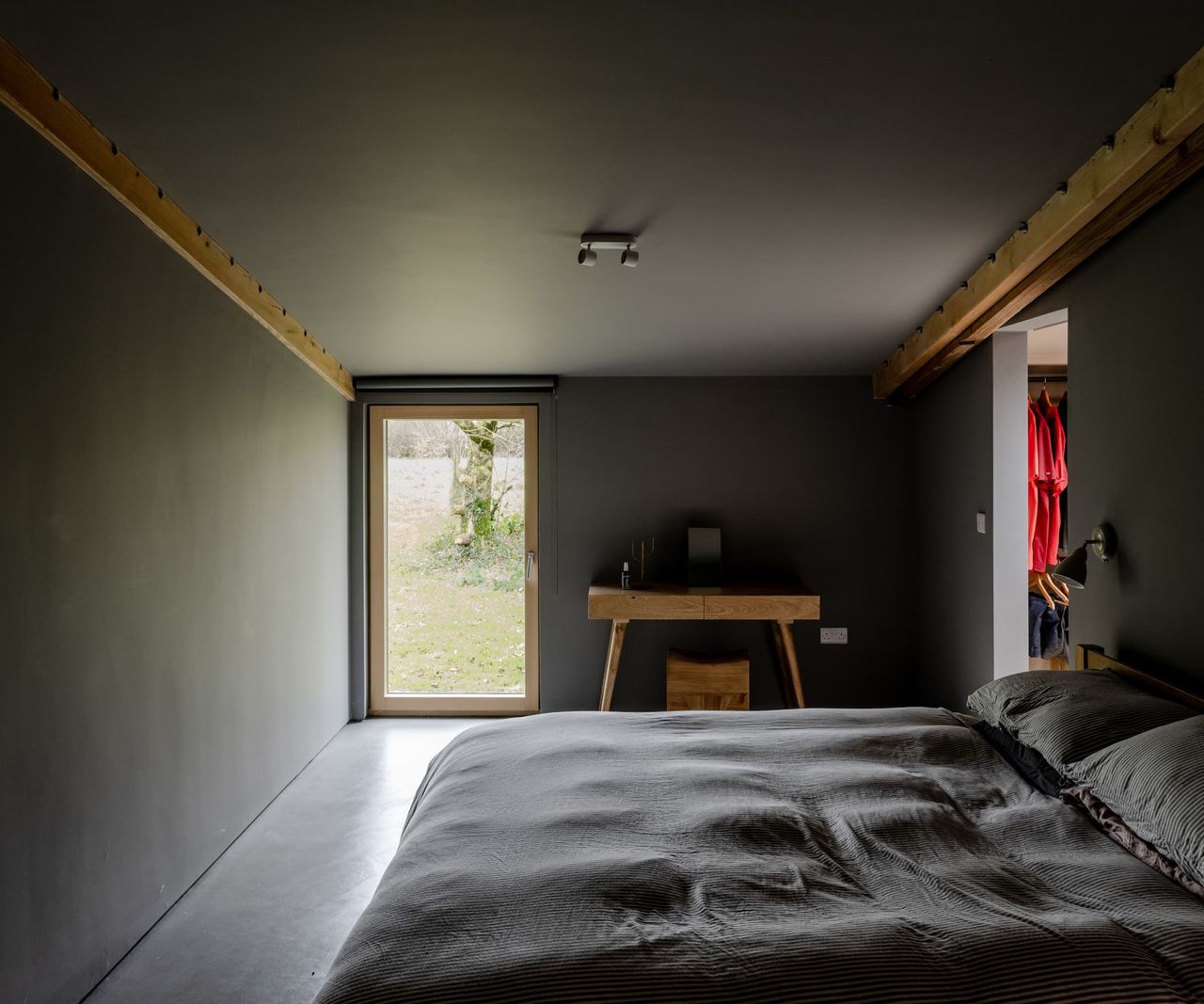 A completely black bedroom with a windowed door and walk in wardrobe