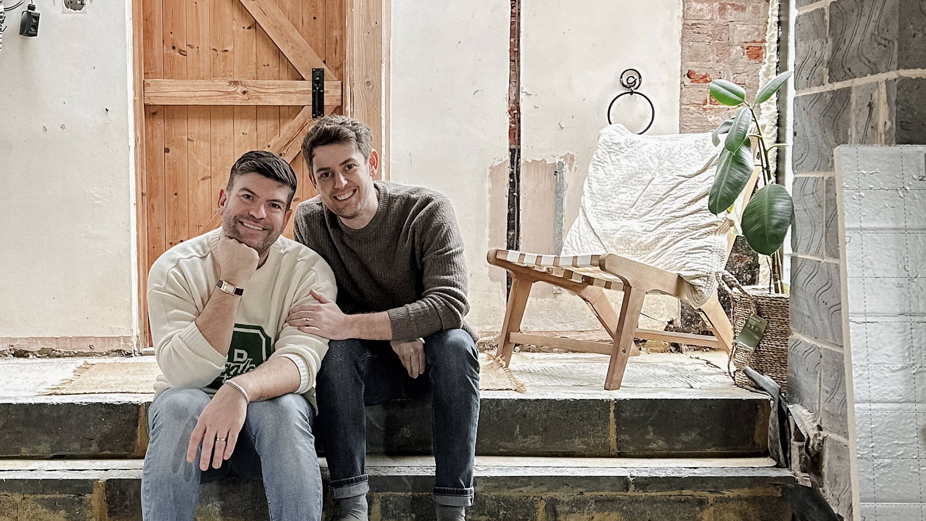 David and Andrew Harrison-Colley pictured at home sitting on a step with a wooden door behind