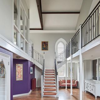 church entrance with white and purple wall and wooden floor and stair case
