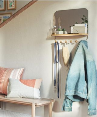 A picture of an entryway with a mirror with hooks and a coat on it