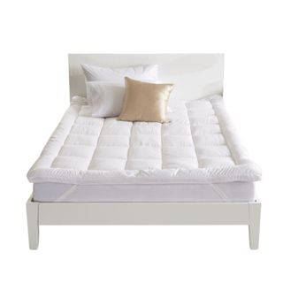 A quilted mattress topper on a white bed
