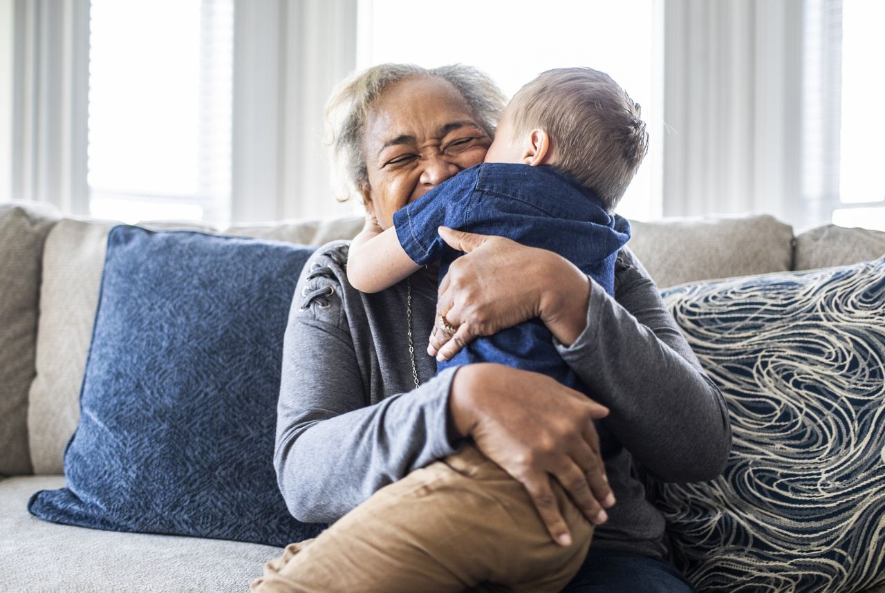 Grandmother embracing toddler grandson and laughing 