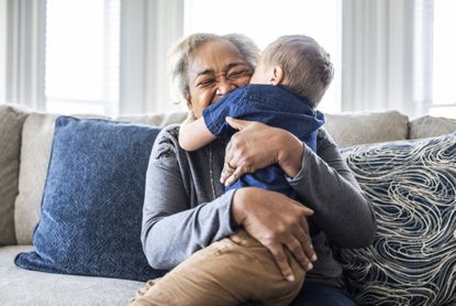 Grandmother embracing toddler grandson and laughing 