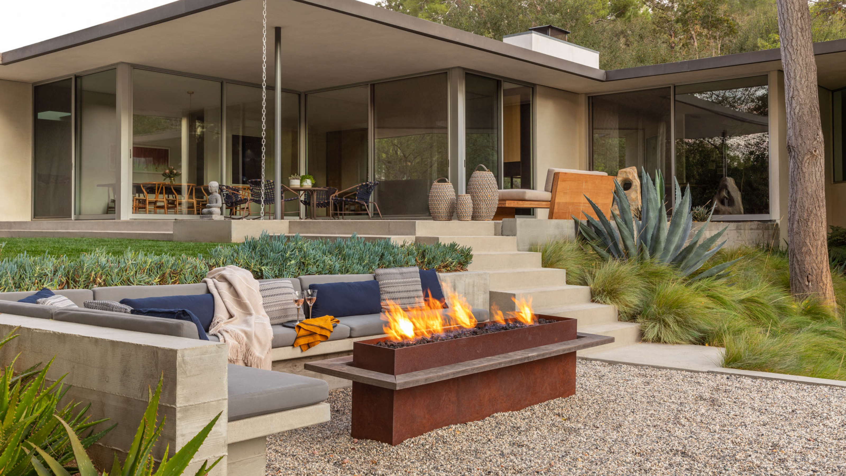 modern chic outdoor area with built-in sofa and a firepit table 