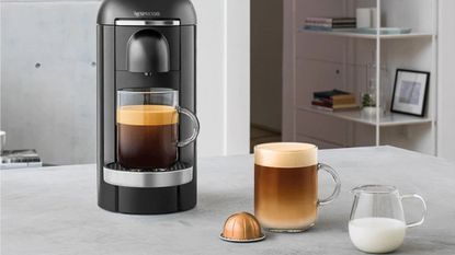 A black Nespresso Vertuo Plus in kitchen with coffee and capsules