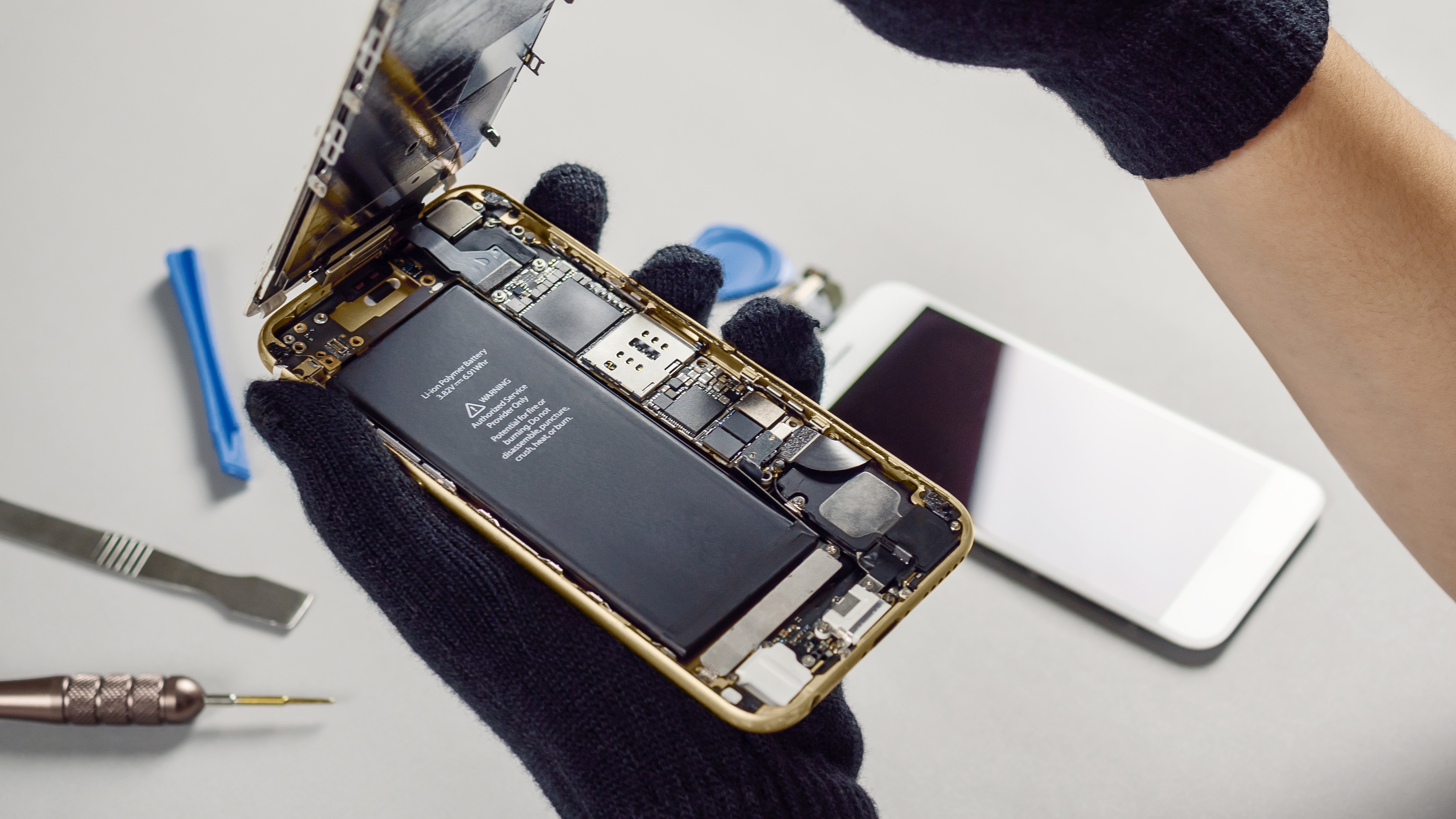 A hand holding a phone with its back removed showing the battery and internals