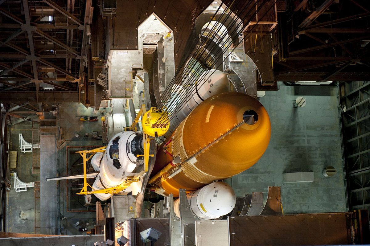 In the Vehicle Assembly Building at NASA&#039;s Kennedy Space Center in Florida, shuttle Endeavour is lowered into place where it is being attached to its external fuel tank and solid rocket boosters, already positioned on the mobile launcher platform. The shu