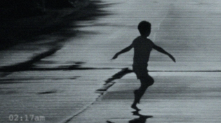 Black and white CCTV footage of a child running with their arms outstretched 
