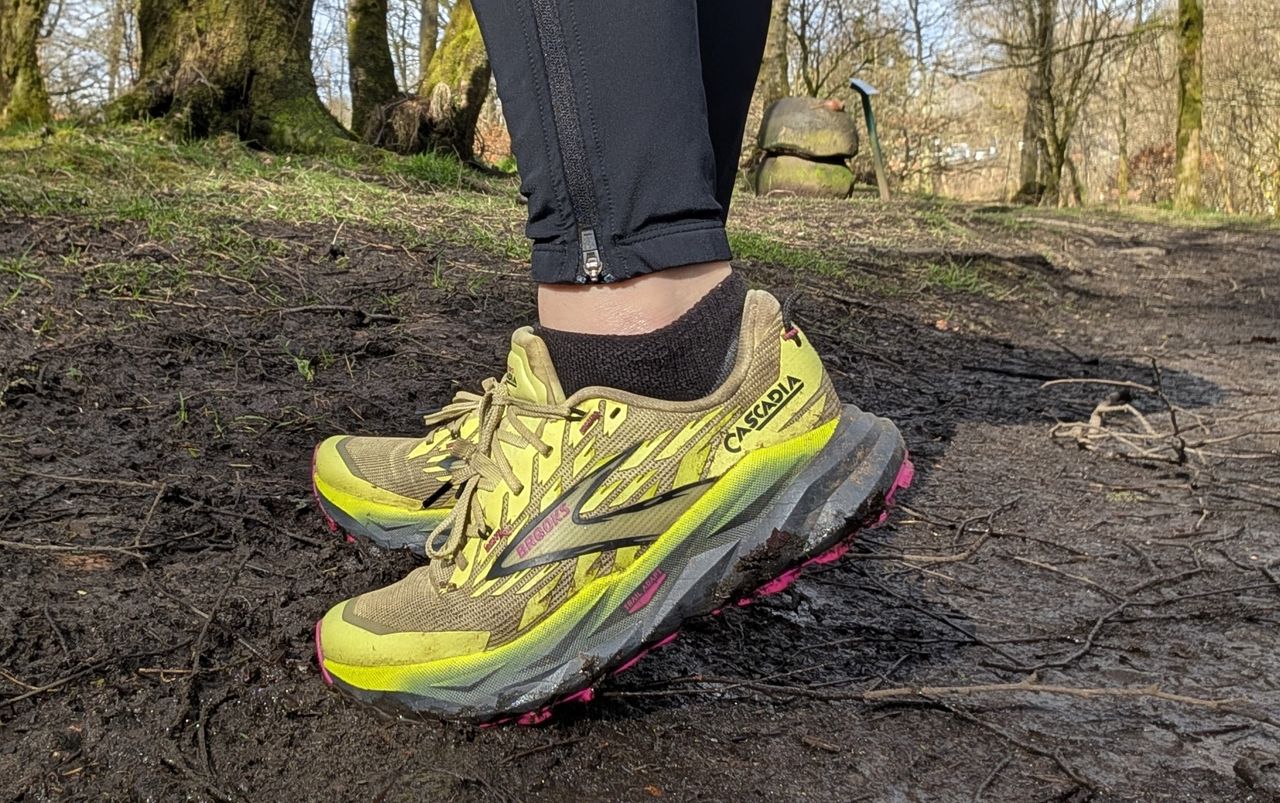 A runner's feet on the trail wearing the Brooks Cascadia 19 shoes in yellow