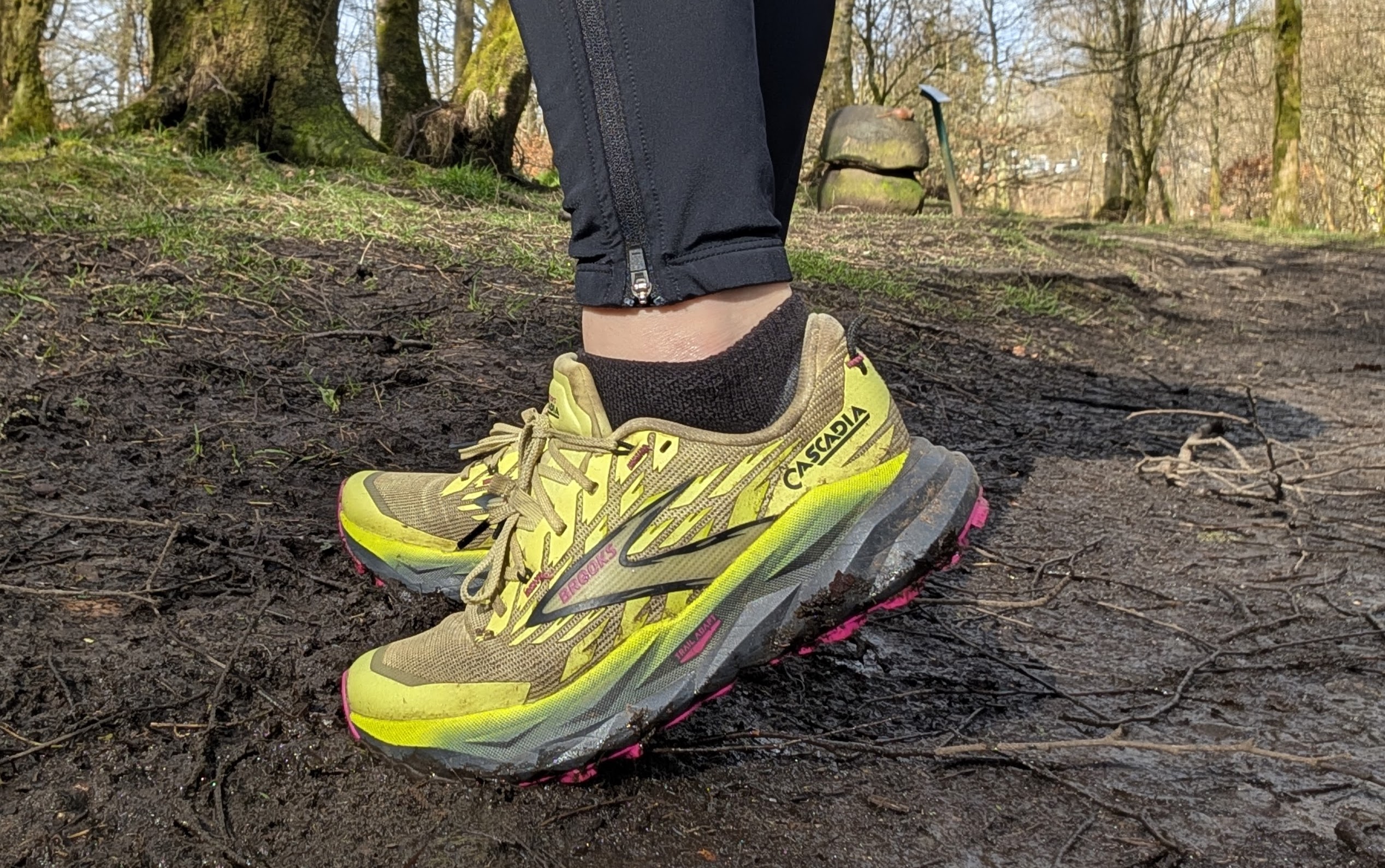 A runner's feet on the trail wearing the Brooks Cascadia 19 shoes in yellow