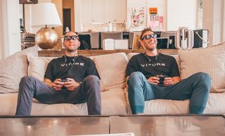 Image of men sitting on a sofa gaming wearing the Viture One XR glasses