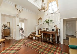 entrance hall with wooden floor and rugs and white wall with staircase