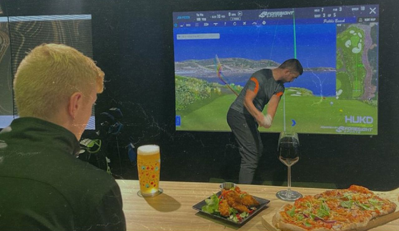 A golfer swings in the simulator 